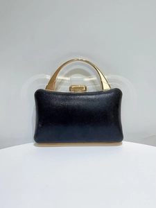 Close-up of black evening clutch with gold metal handle and luxury glitter texture detail