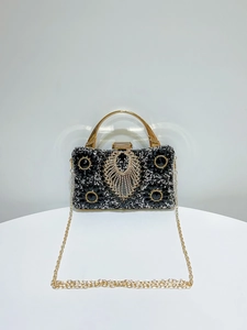 Detail of black rhinestone evening bag featuring gold metal handle and crystal feather motif