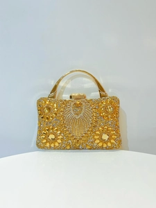 Close-up of luxury gold evening bag featuring intricate floral rhinestone and jewel inlay