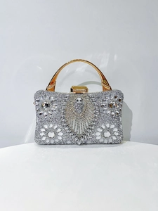 Detail of silver evening bag featuring luxury rhinestones and golden arched top handle