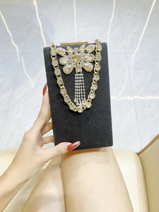 Detail of a black glitter evening clutch with a gemstone butterfly and gold chain