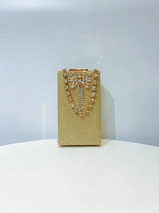 Close-up of golden glitter evening clutch with crystal butterfly clasp and metal chain