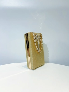 Detail of gold glitter evening clutch bag with crystal bow decoration and metal frame