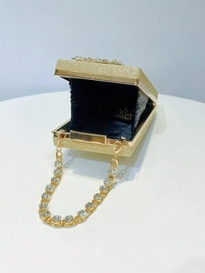 Macro detail of a gold glitter evening clutch bag with sparkling rhinestone chain strap
