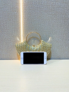 Macro detail of a fan-shaped golden evening clutch with beads and sparkling rhinestones