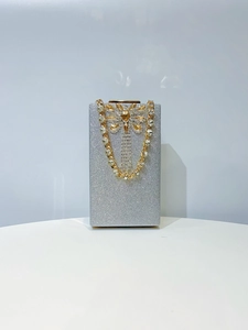 Detail of silver glitter clutch bag with gold crystal butterfly clasp and chain strap