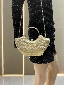 Detail of golden fan-shaped evening clutch bag with sparkling rhinestones and beaded tassels