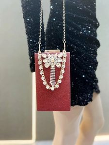 Detail of red glitter evening clutch with silver rhinestone butterfly and fringe tassels