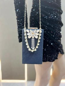 Detail view of navy velvet clutch bag with rhinestone bow and sparkling tassel decoration