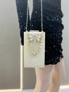 Detail of a gold evening clutch featuring rhinestone butterfly and shimmering glitter finish