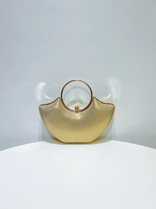 Macro detail of gold glitter evening bag with large metal ring handle and snap closure