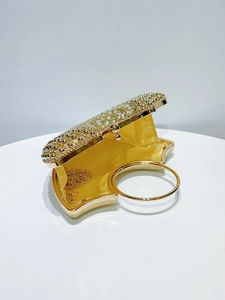 Macro view of gold evening clutch featuring dense rhinestones and yellow satin lining