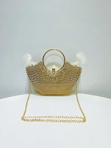 Close-up of golden evening bag featuring sparkling rhinestones and metal ring handle