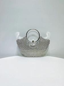 Detailed macro view of luxury silver evening bag featuring rhinestone pattern and metal tassels