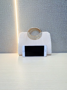 Ruched evening clutch with rhinestone ring handle shown next to smartphone for size