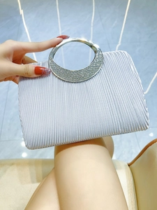 Detailed view of silver pleated evening clutch with rhinestone encrusted round metal handle