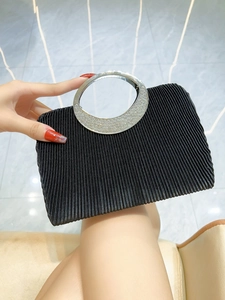 Detail of black pleated evening clutch with crystal-embellished round metal handle