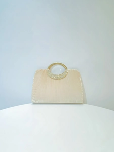 Macro detail of apricot pleated satin fabric and rhinestone-studded golden ring handle