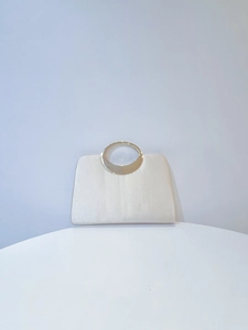 Detail of elegant cream pleated satin evening clutch with round gold metal handle