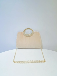 Detail of evening clutch featuring pleated fabric, gold ring handle, and rhinestones