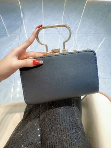 Close-up of elegant black evening clutch with luxury gold metal handle and texture