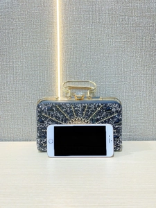 Macro shot of silver crystal peacock pattern on the evening clutch with metal handle