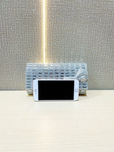 Silver rhinestone evening clutch bag shown next to a smartphone for size reference