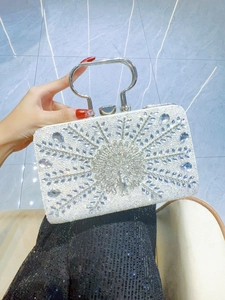 Close-up of luxury evening bag with peacock rhinestone relief and silver metal handle