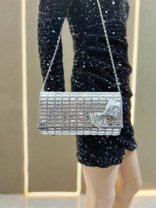 Detail of silver rhinestone clutch bag with a large sparkling bow and metal chain strap