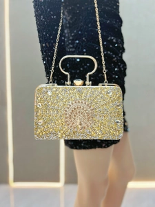 Close-up of luxury rhinestone peacock evening clutch bag worn with black sequin dress