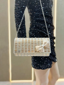 Close-up of luxury rhinestone evening clutch with crystal bow and metal chain strap