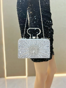 Detail of silver evening clutch bag with peacock crystal pattern held by a model