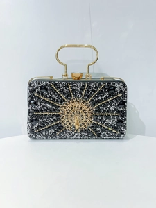 Detailed close-up of a luxury evening clutch with peacock pattern and sparkling crystals