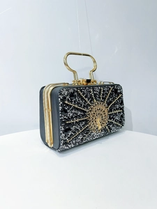 Detail view of the intricate gold peacock ornament on this luxury evening clutch bag
