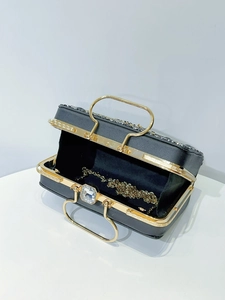 Detail of black evening clutch with gold U-handle, sequins, and detachable chain strap