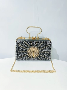 Detailed view of luxury peacock evening bag with black rhinestones and gold handle