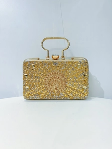 Macro view of gold evening clutch featuring rhinestone peacock relief and gem buckle