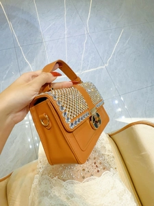 Orange-brown leather handbag with sparkling rhinestone accents and gold twist lock