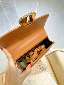 Brown leather handbag with gold metal clasp and adjustable shoulder strap shown open