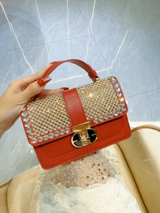 Detail of red leather handbag featuring sparkling rhinestones and a gold metal buckle