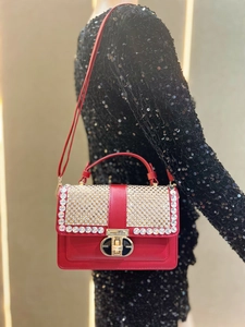 Detail of red leather handbag featuring sparkling rhinestone flap and golden twist lock