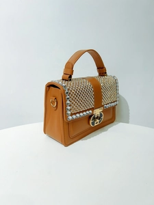 Detail of orange-brown leather handbag with sparkling rhinestone flap and gold metal lock
