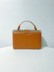 Detailed view of brown leather handbag with sparkling rhinestone flap and top handle
