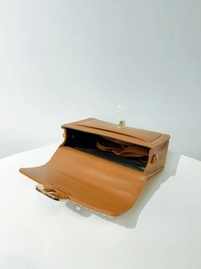 Overhead detail view of brown faux leather handbag with gold clasp and detachable strap
