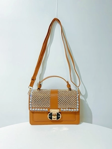 Close-up of brown handbag with rhinestone-studded flap and gold metal twist lock
