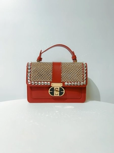 Detailed close-up of red leather handbag with sparkling rhinestone flap and gold hardware