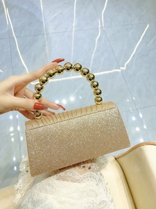Detail of elegant gold pleated evening clutch with pearl handle and shimmering sequins