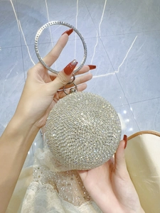 Detail of round dinner clutch featuring a silver ring handle and sparkling rhinestones