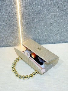 Macro view of golden sequin evening clutch with large pearl handle and interior storage