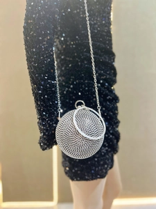 Sparkling spherical evening bag with rhinestones and silver handle held by a model